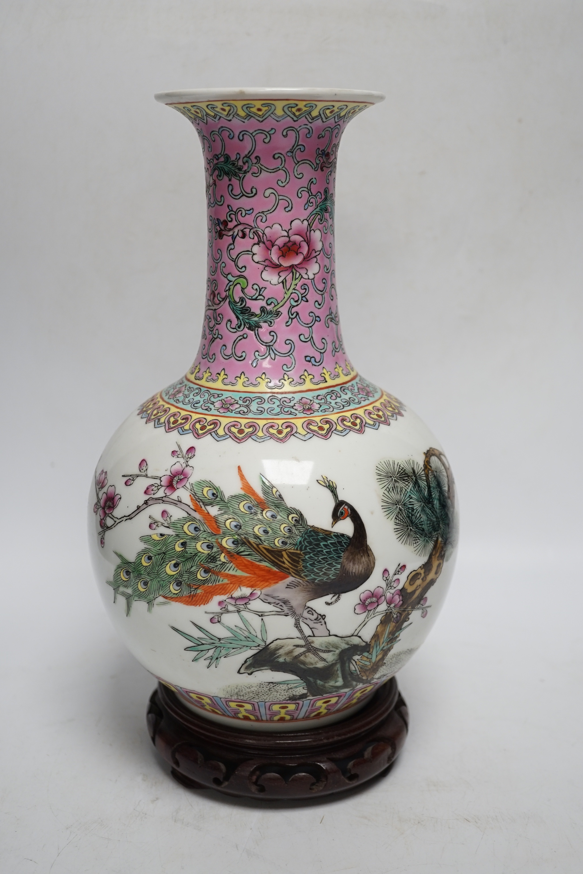 A pair of large Chinese soapstone ‘Temple Guardian lion’ seals, 21cm, and a Chinese famille rose vase, 27cm, on carved wood stand